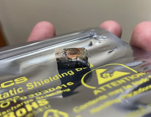 The same block of potting compound and chip from a lower angle, on the anti-static bag held in a hand.
